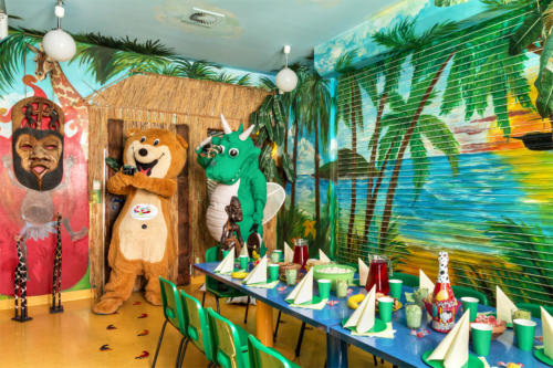 Na zdjęciu znajdują się maskotki Miś Bobuś oraz Smok Fampo w pokoju urodzinowym Dżungla.